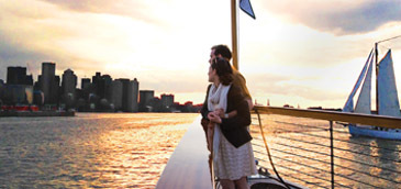 Romantic couple aboard a private yacht during sunset over Boston Harbor