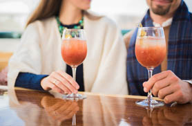 A man and woman enjoying cocktails at a bar.