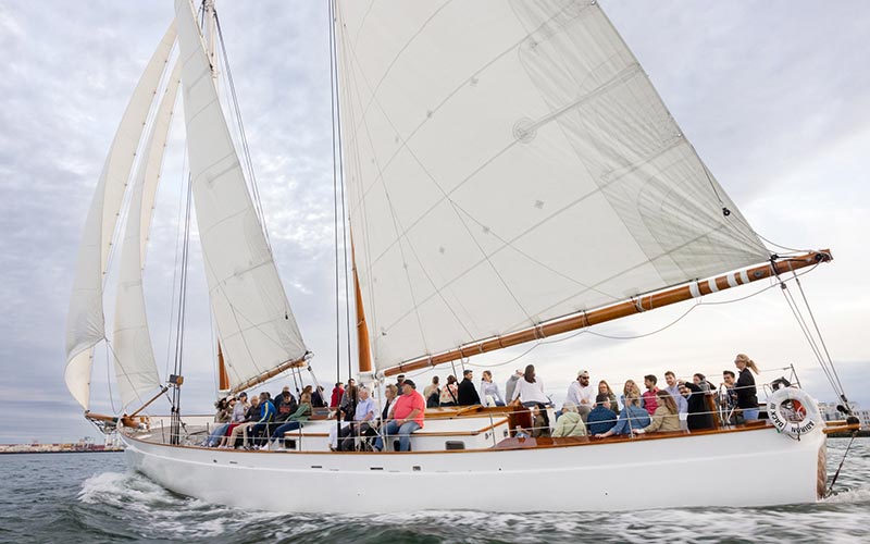 a schooner adirondack sailboat, sailing down a river in Boston