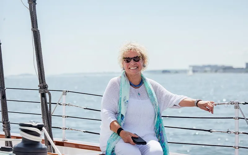 a middle aged woman smiling and sitting on a sailboat