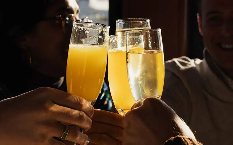 a group of people cheersing glasses of mimosa