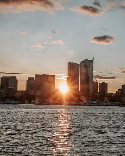 the sunset piercing between the buildings in downtown Boston