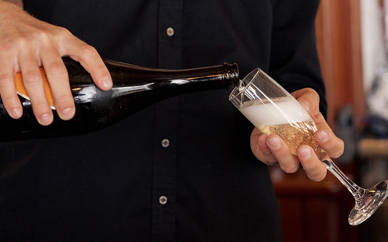 closeup of a yacht crewman pouring champagne into a glass