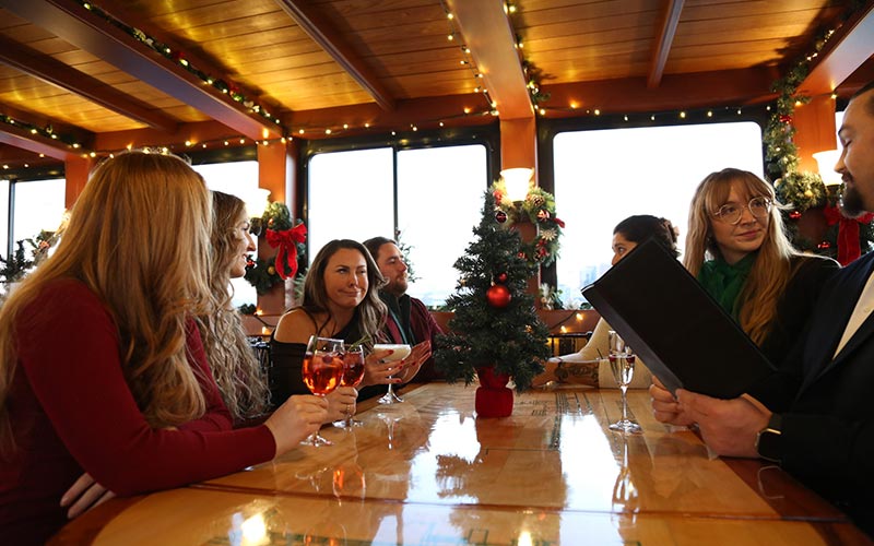 a group of people sitting at a table inside of a motor yacht, drinking and socializing