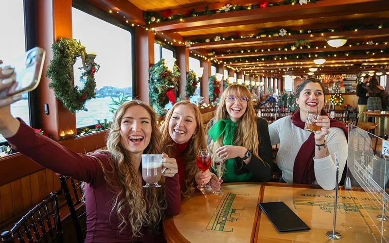 a group of three women taking a selfie together, aboard a holiday decorated motor yacht