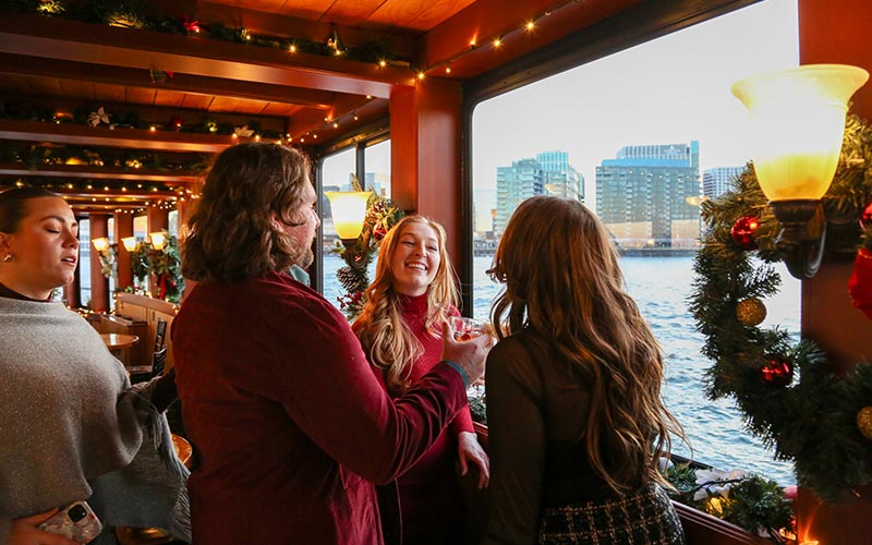 a group of women socializing with drinks, inside of a motor yacht