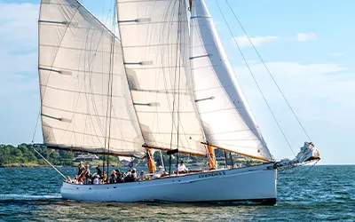 the Schooner Adirondack II sailboat, full of passengers, cruising down a river in Boston