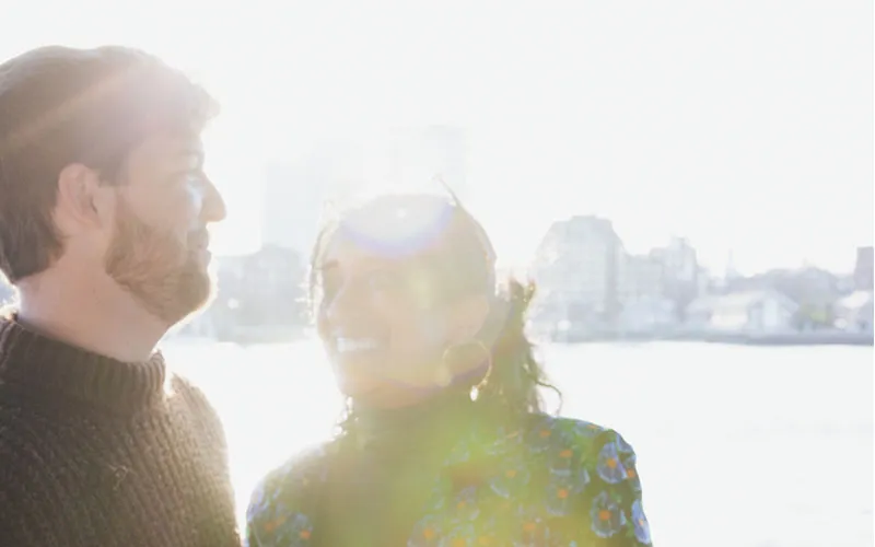 Boston_Northern-Lights-Sunset-Slider-3 closeup of a man and woman smiling at each other, with the sunlight piercing their faces