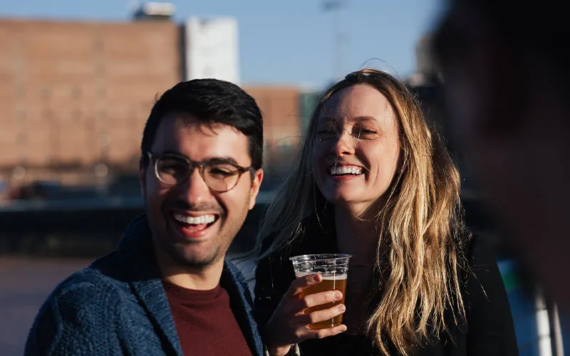 Boston_Northern-Lights-Sunset-Slider-5 closeup of a man and a woman smiling, while one is holding a drink
