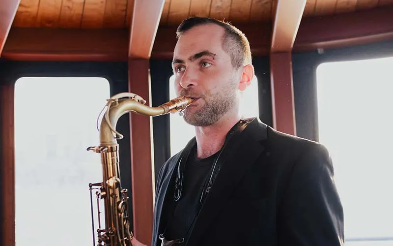 closeup of a man playing the saxophone, while on the inside of a motor yacht