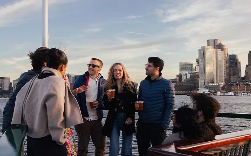 a group of friends, standing aboard a motor yacht in boston, holding drinks and socializing
