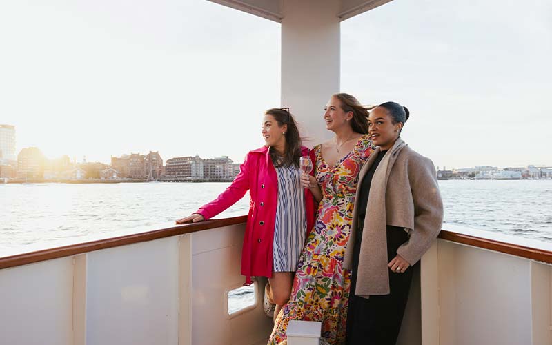 three women smiling while aboard the yacht Northern Lights, while looking out over the water