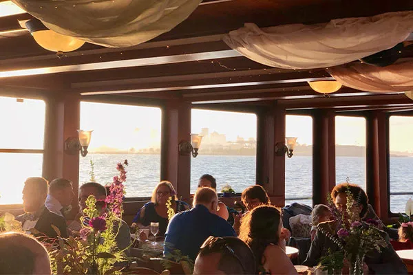 groups of people sitting, eating and drinking inside of a motor yacht in boston