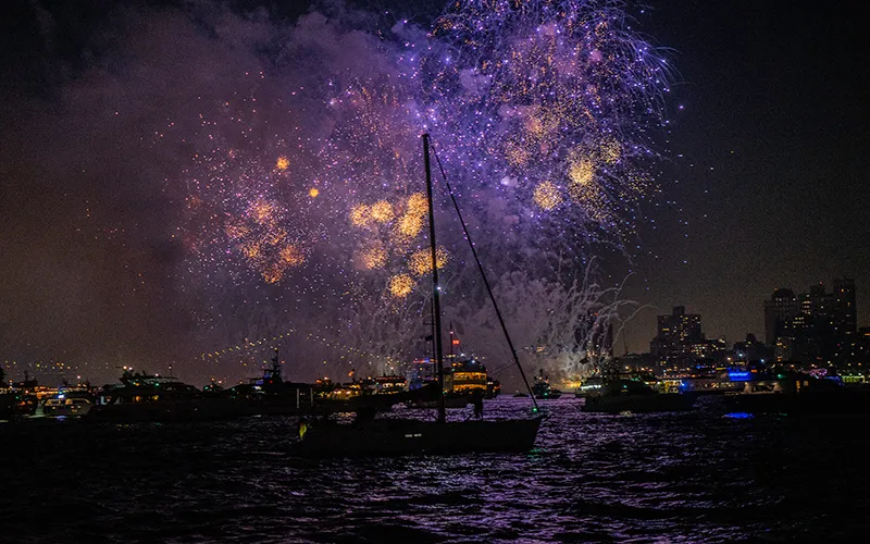 Boats on the water with fireworks in the sky
