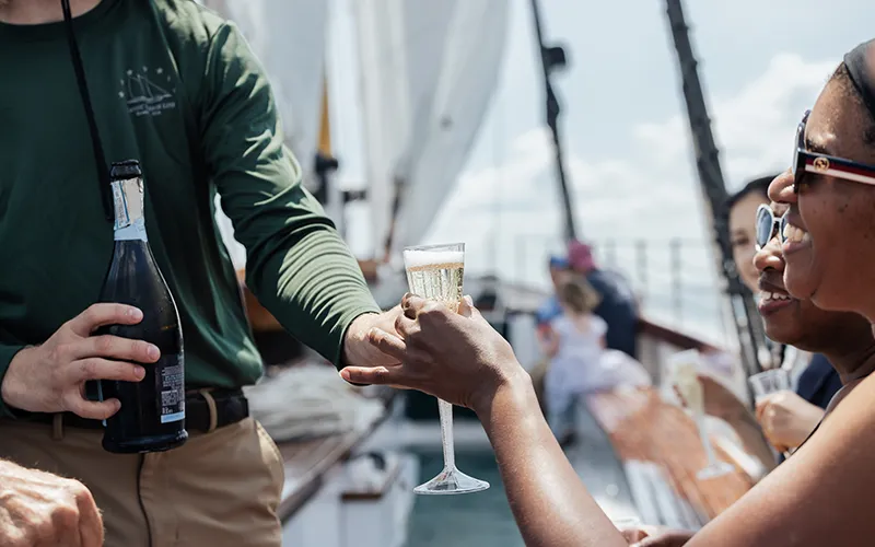 Crew member serving champagne to a customer on schooner Adirondack III