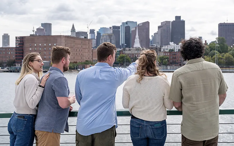 Guests on the bow of yacht Northern Lights with the Boston Skyline in the background for a sightseeing cruise