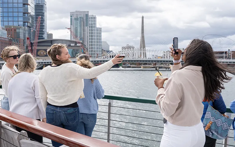 Guests on the bow of yacht Northern Lights with the Boston Skyline in the background for a sightseeing cruise