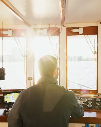 a man sitting in the captain's quarters looking out over the water