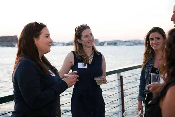 Boston_Corporate-Events-Plan-Your-Event two women, holding drinks, chatting and smiling while aboard a motor yacht