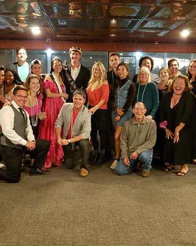 a large group of people bending down and posing for a photo, while all smiling inside of a motor yacht