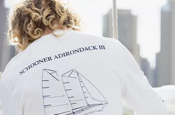 a crewman working aboard a sailboat, with the words on her shirt that reads "Schooner Adirondack III"