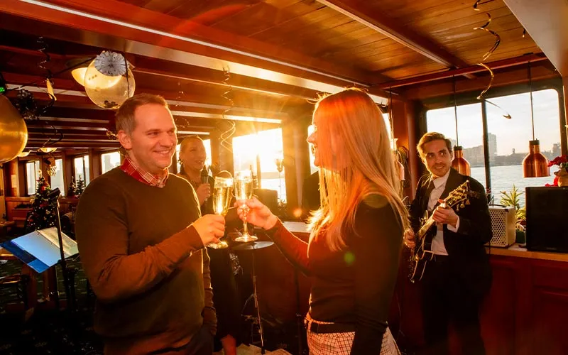 A couple enjoying music and clicking glasses in the grand salon of yacht Northern Lights in Boston Harbor