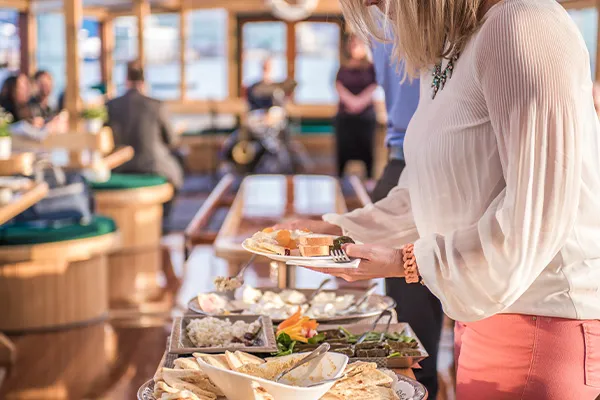closeup of a woman grabbing food from a buffet line, while aboard a motor yacht