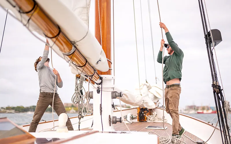 Crew raising sails on the Schooner Adirondack in Boston Harbor
