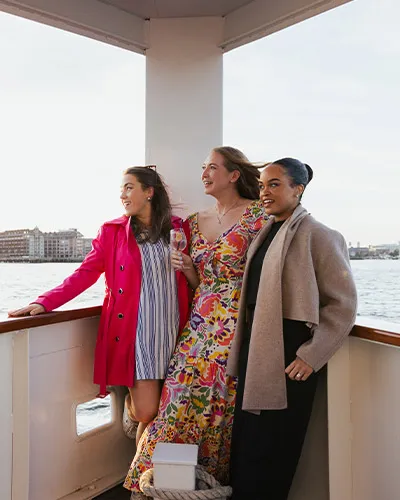 three women smiling while aboard the yacht Northern Lights, while looking out over the water - Specialty Cruises with Classic Harbor Line Boston