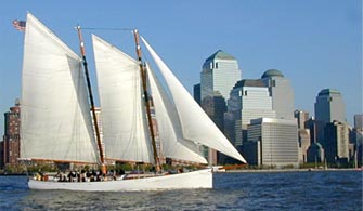 the Schooner Adirondack sailboat cruising down a river with New York City in the background