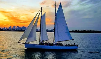 the Schooner Adirondack III sailboat, cruising down a river for a sunset cruise