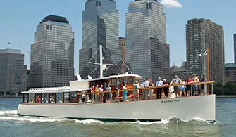 the Yacht Manhattan, cruising down the river with New York City in the background