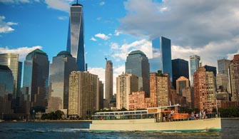 the motor yacht Manhattan II cruising down a river with New York City in the background