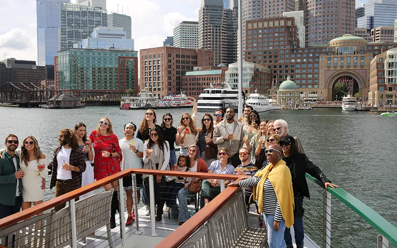 Large Group on the bow of yacht Northern Lights with the Boston Harbor Hotel in the background