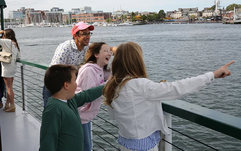 A man and his children on a boat pointing at the sights