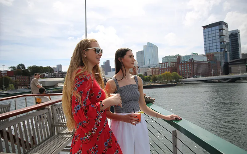 Two friends on the bow of yacht Northern Lights with the Boston Skyline in the background