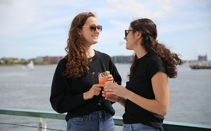 Two friends enjoying cocktails on a sightseeing boat ride in Boston Harbor aboard the Yacht Northern Lights