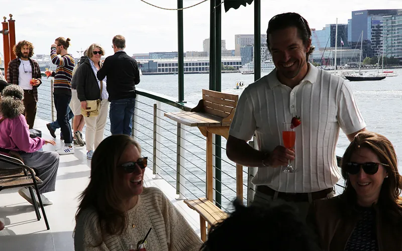 Group of friends enjoying cocktails on a boat in Boston Harbor and the skyline in the background