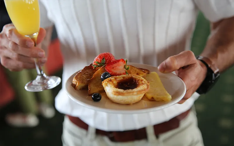 Plate of food with a person holding a mimosa