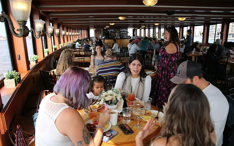 Group of friends sitting at a table in the grand salon of the yacht Northern Lights enjoying brunch