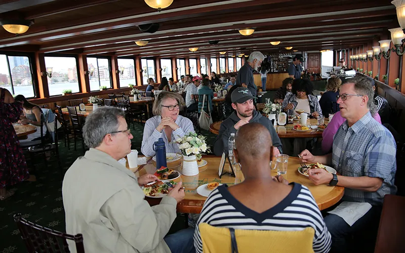 Group of friends sitting at a table in the grand salon of the yacht Northern Lights enjoying brunch