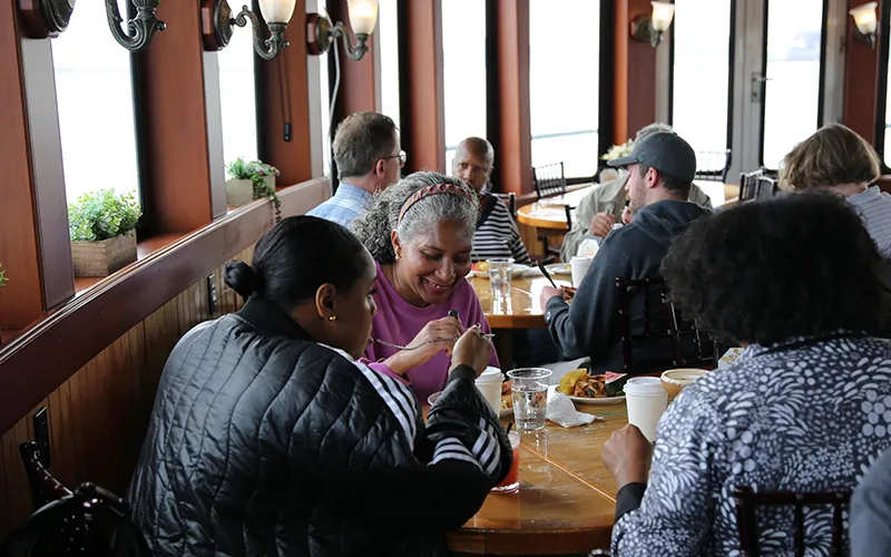 Group of friends sitting at a table in the grand salon of the yacht Northern Lights enjoying brunch
