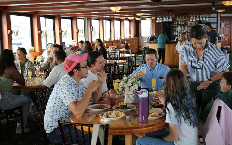 Group of friends sitting at a table in the grand salon of the yacht Northern Lights enjoying brunch