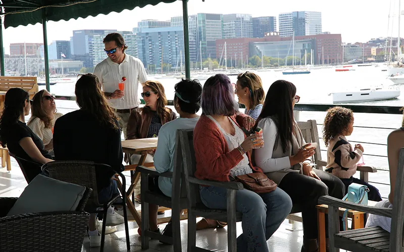 Group of friends enjoying cocktails on a boat in Boston Harbor and the skyline in the background
