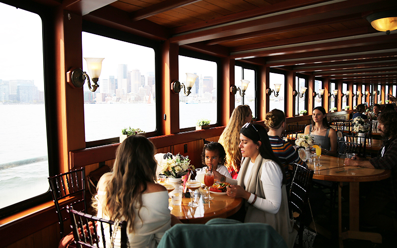Group of friends sitting at a table in the grand salon of the yacht Northern Lights enjoying brunch