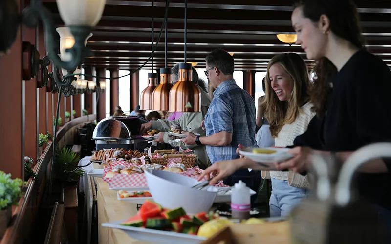 Guests serving themselves at a buffet for a Boston Brunch Cruise in the grand salon of yacht Northern Lights