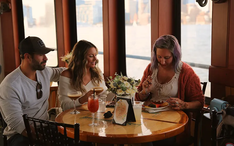 Friends enjoying mimosas and food in the grand salon of the yacht Northern Lights