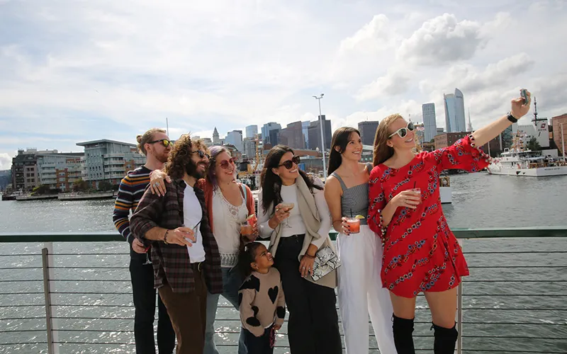 Group of Friends taking a sightseeing cruise and a selfie on the bow of yacht Northern Lights with the Boston Skyline in the background