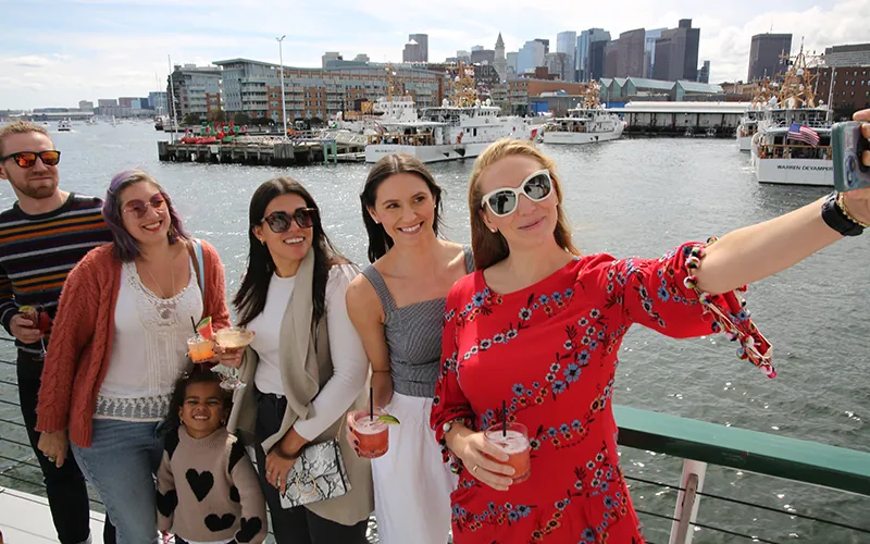 Group of Friends taking a sightseeing cruise and a selfie on the bow of yacht Northern Lights with the Boston Skyline in the background