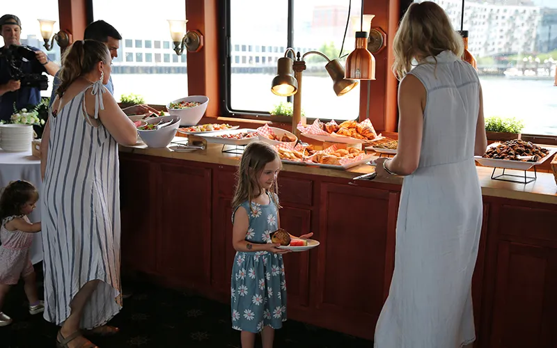 A mother and her child getting food at a buffet table